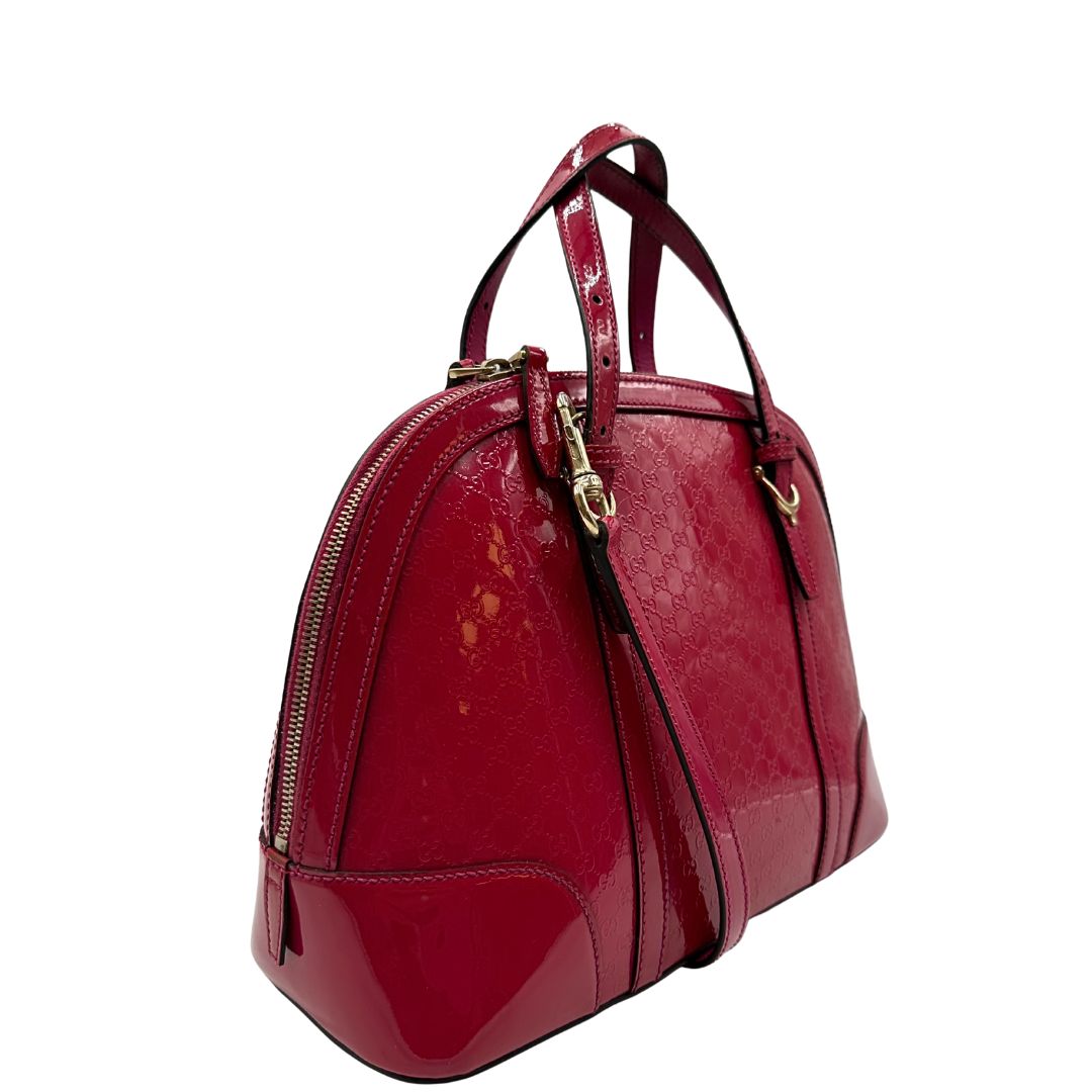 lato Borsa Gucci in pelle verniciata rosso fragola rifinita con inserti metallici oro chiaro; munita di doppi manici e una tracolla regolabile e amovibile 