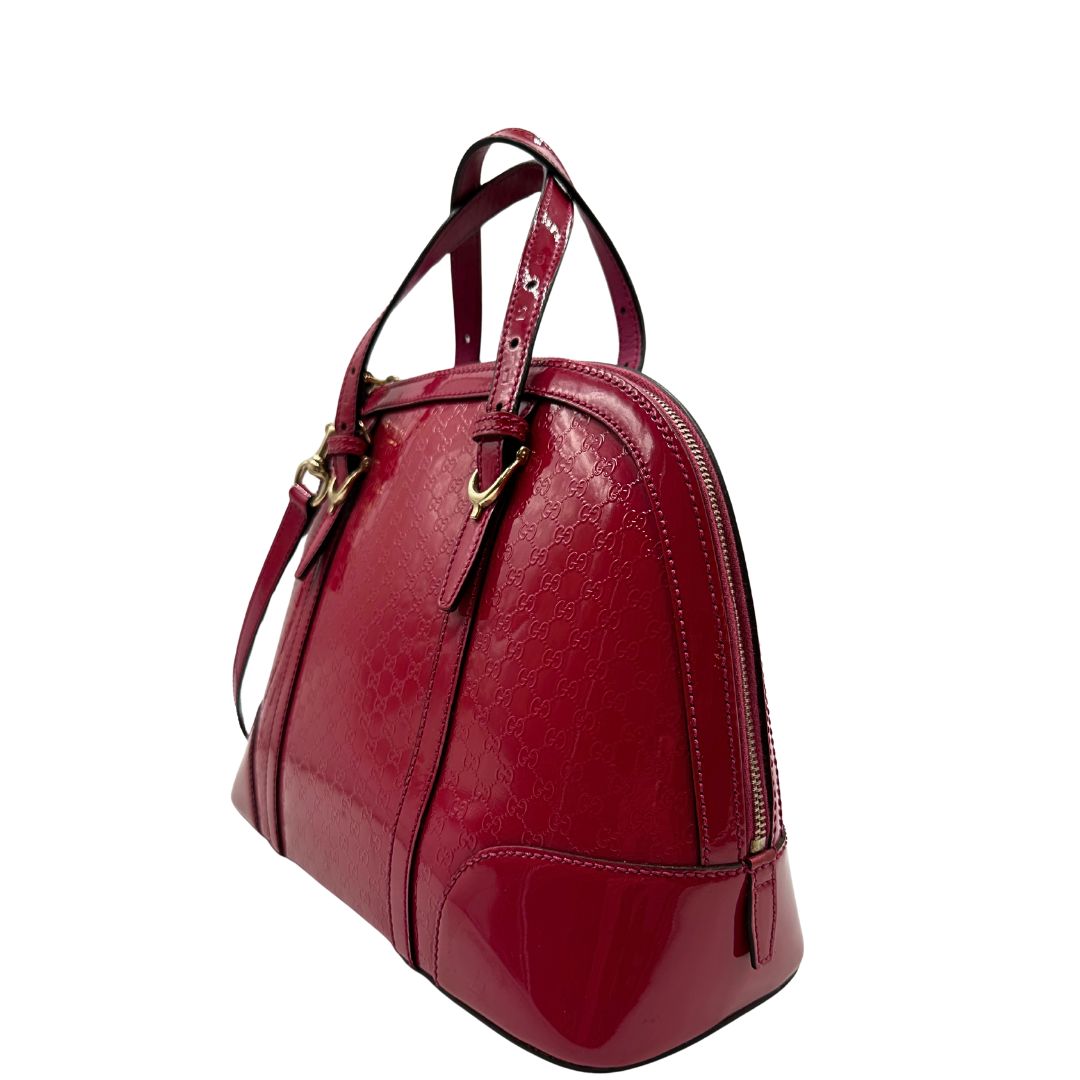 lato Borsa Gucci in pelle verniciata rosso fragola rifinita con inserti metallici oro chiaro; munita di doppi manici e una tracolla regolabile e amovibile 