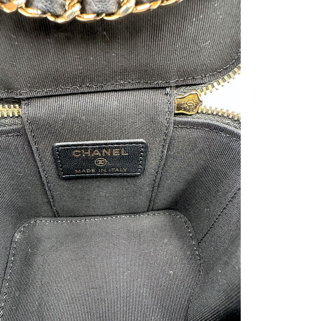 Interno di una borsa Chanel in pelle matelassè nera rifinita con parti metalliche dorate; munita di una tracolla in pelle e catena intrecciata decorata con fiocco e camelia. Completa di scatola logata.