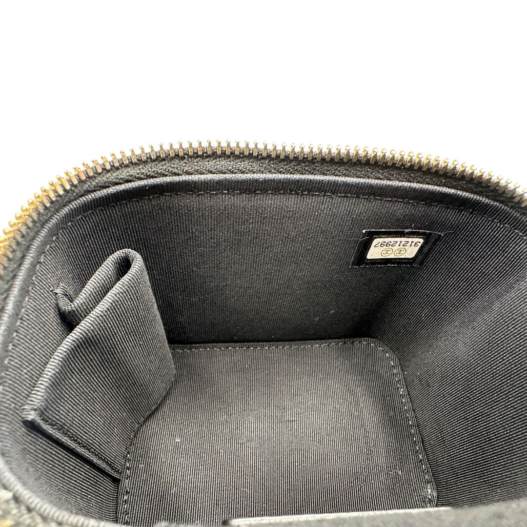 Interno di una borsa Chanel in pelle matelassè nera rifinita con parti metalliche dorate; munita di una tracolla in pelle e catena intrecciata decorata con fiocco e camelia. Completa di scatola logata.