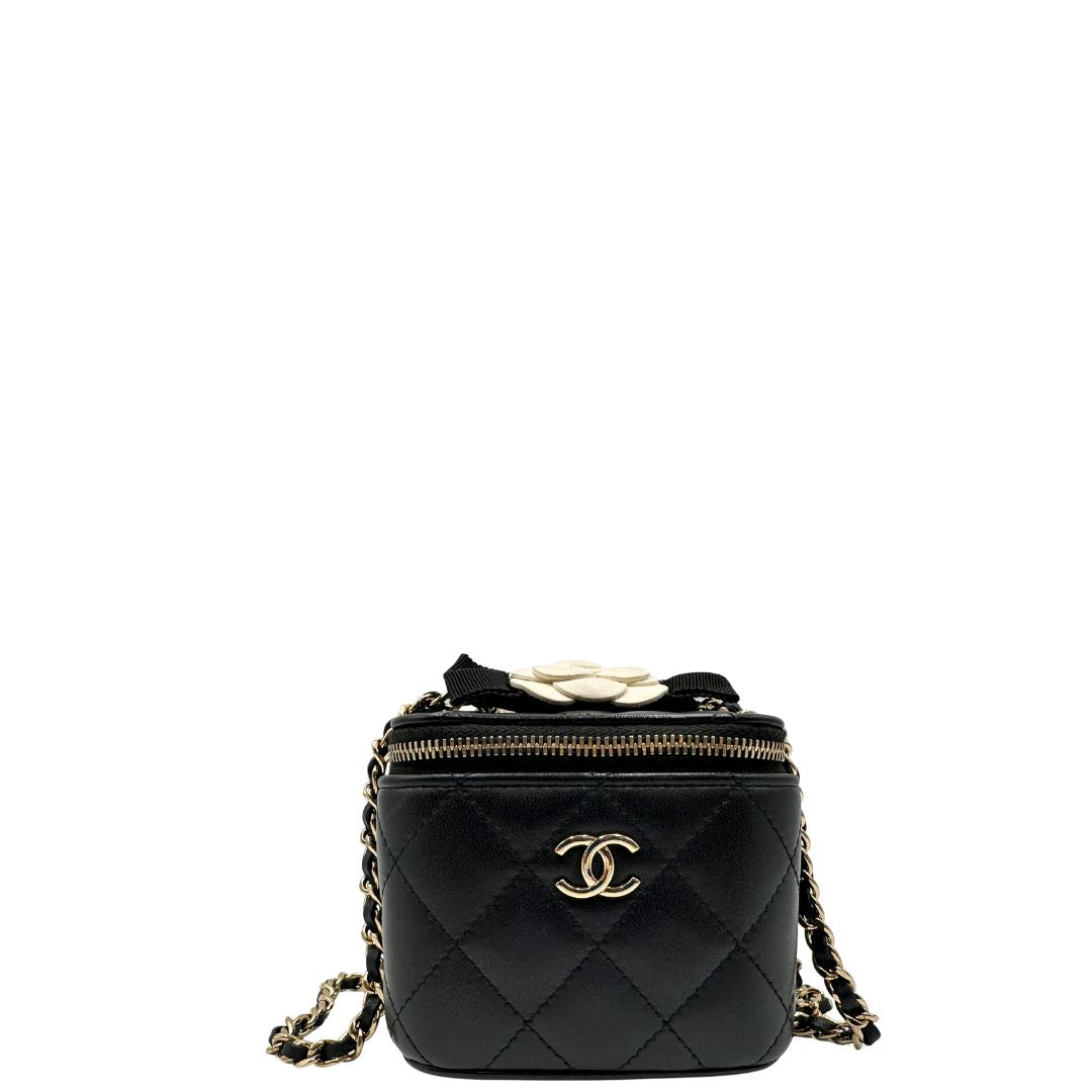 Front di una borsa Chanel in pelle matelassè nera rifinita con parti metalliche dorate; munita di una tracolla in pelle e catena intrecciata decorata con fiocco e camelia. Completa di scatola logata.