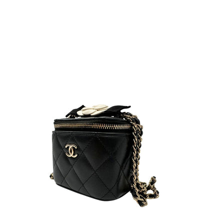 Laterale destro di una borsa Chanel in pelle matelassè nera rifinita con parti metalliche dorate; munita di una tracolla in pelle e catena intrecciata decorata con fiocco e camelia. Completa di scatola logata.