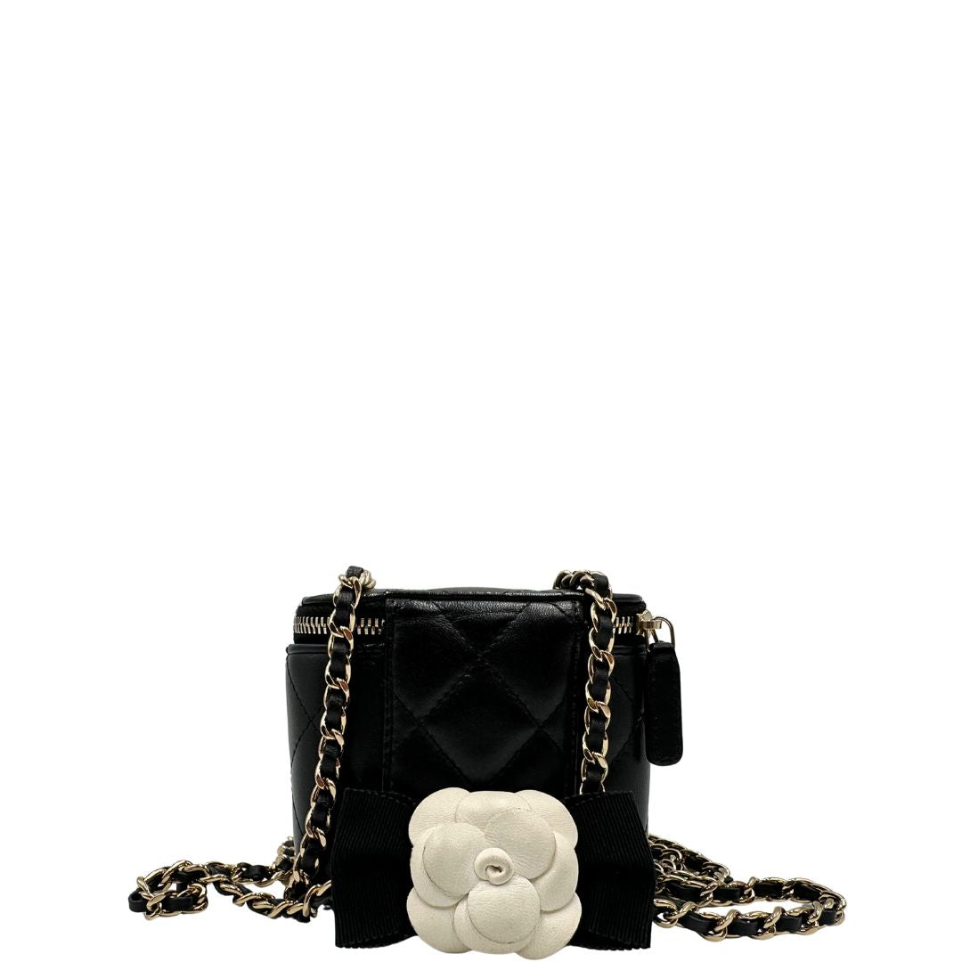 Retro di una borsa Chanel in pelle matelassè nera rifinita con parti metalliche dorate; munita di una tracolla in pelle e catena intrecciata decorata con fiocco e camelia. Completa di scatola logata.