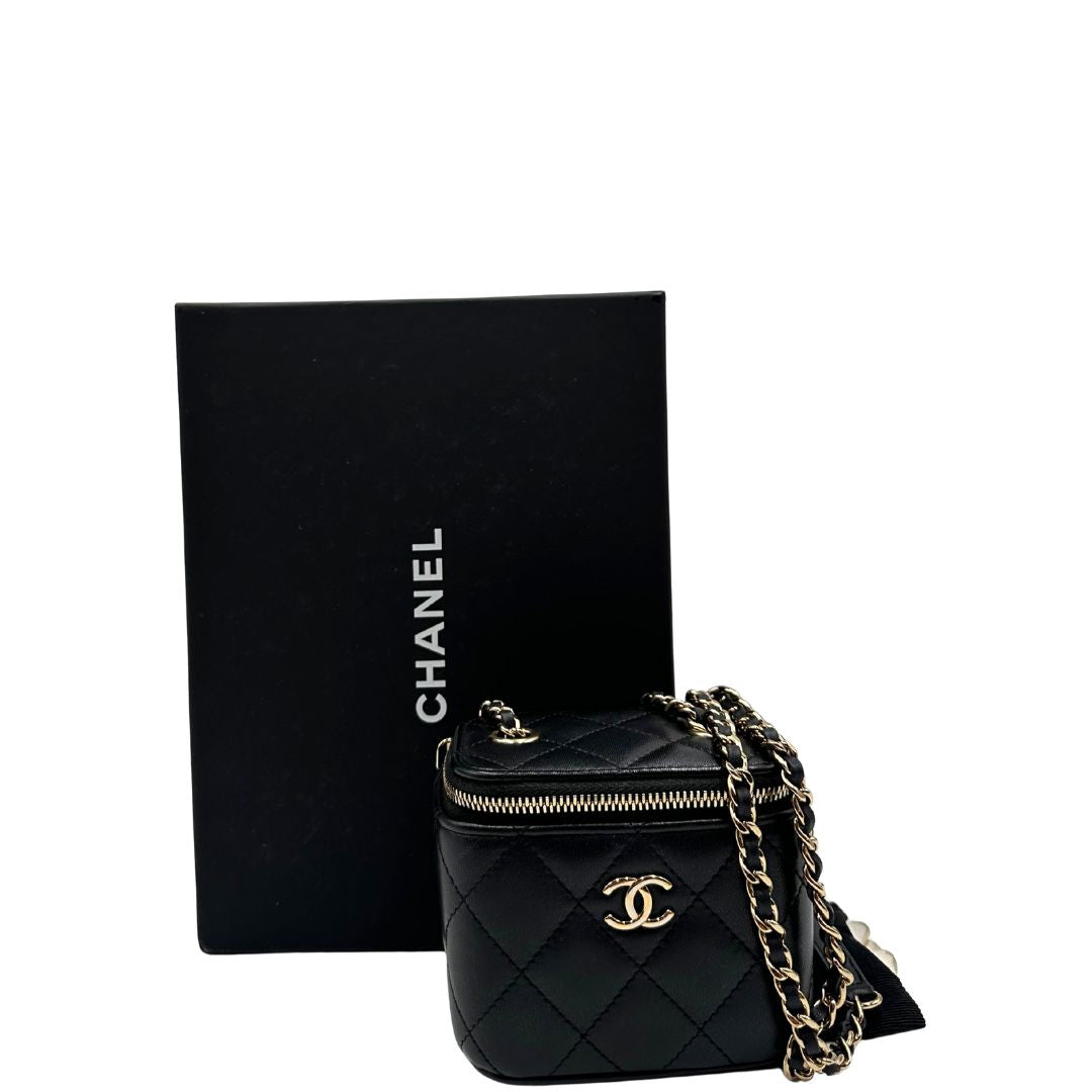 Borsa Chanel in pelle matelassè nera rifinita con parti metalliche dorate; munita di una tracolla in pelle e catena intrecciata decorata con fiocco e camelia. Completa di scatola logata.