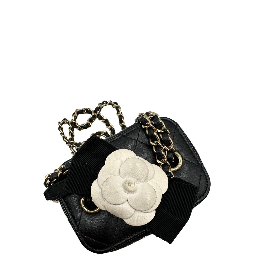 Dettaglio decorativo della tracolla di una borsa Chanel in pelle matelassè nera rifinita con parti metalliche dorate; munita di una tracolla in pelle e catena intrecciata decorata con fiocco e camelia. Completa di scatola logata.