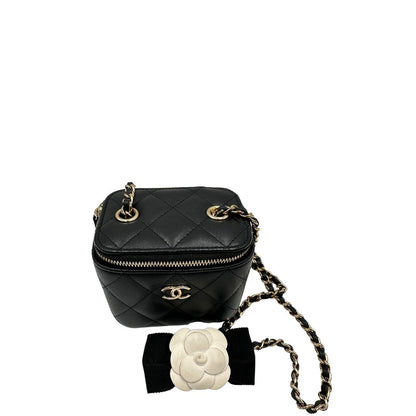 Vista dall'alto di una borsa Chanel in pelle matelassè nera rifinita con parti metalliche dorate; munita di una tracolla in pelle e catena intrecciata decorata con fiocco e camelia. Completa di scatola logata.