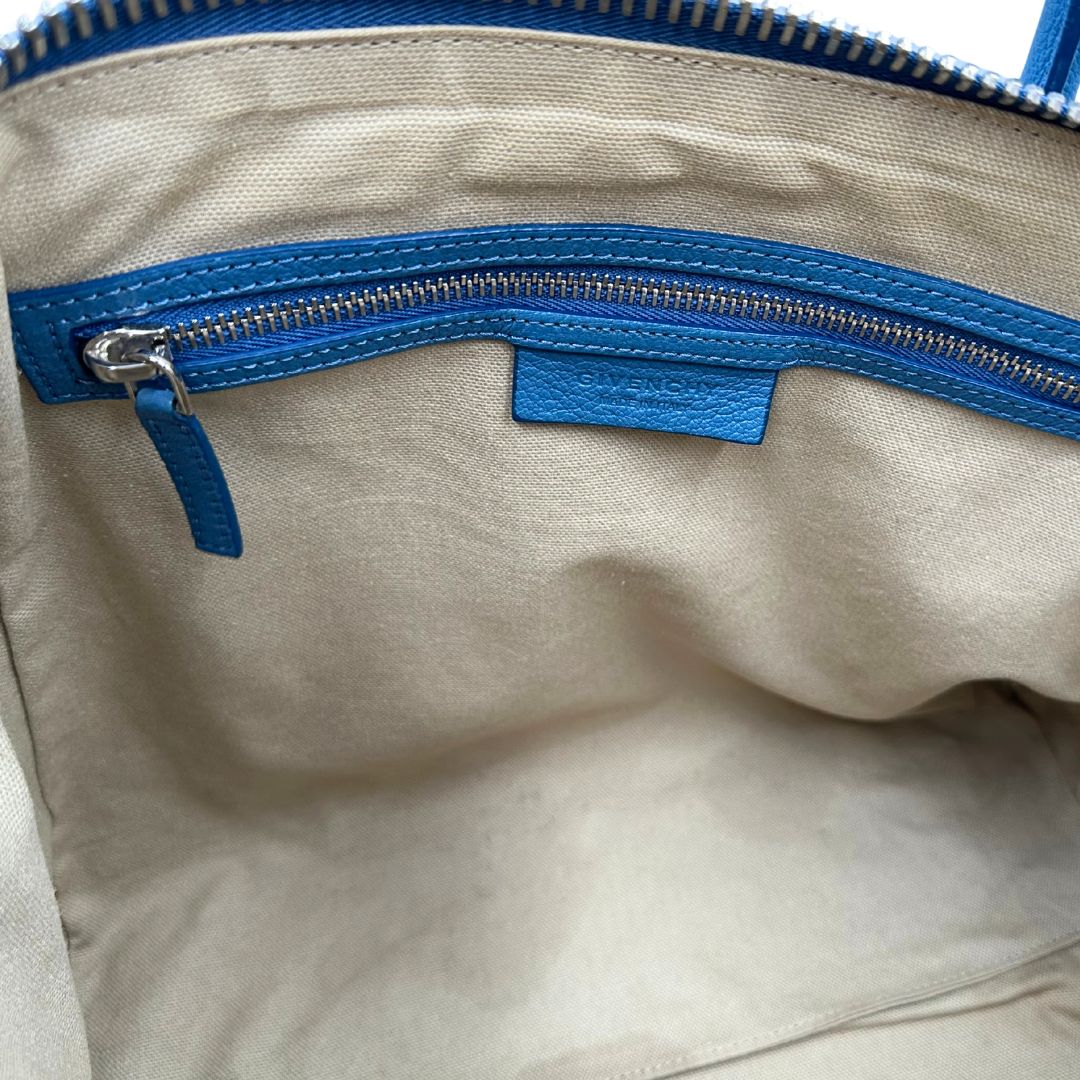 Borsa Givenchy Antigona in pelle martellata blu petrolio munita di doppi manici stondati e tracolla. Parti metalliche argentate. Completa di dustbag. Originale, usato, in condizioni ottime. 