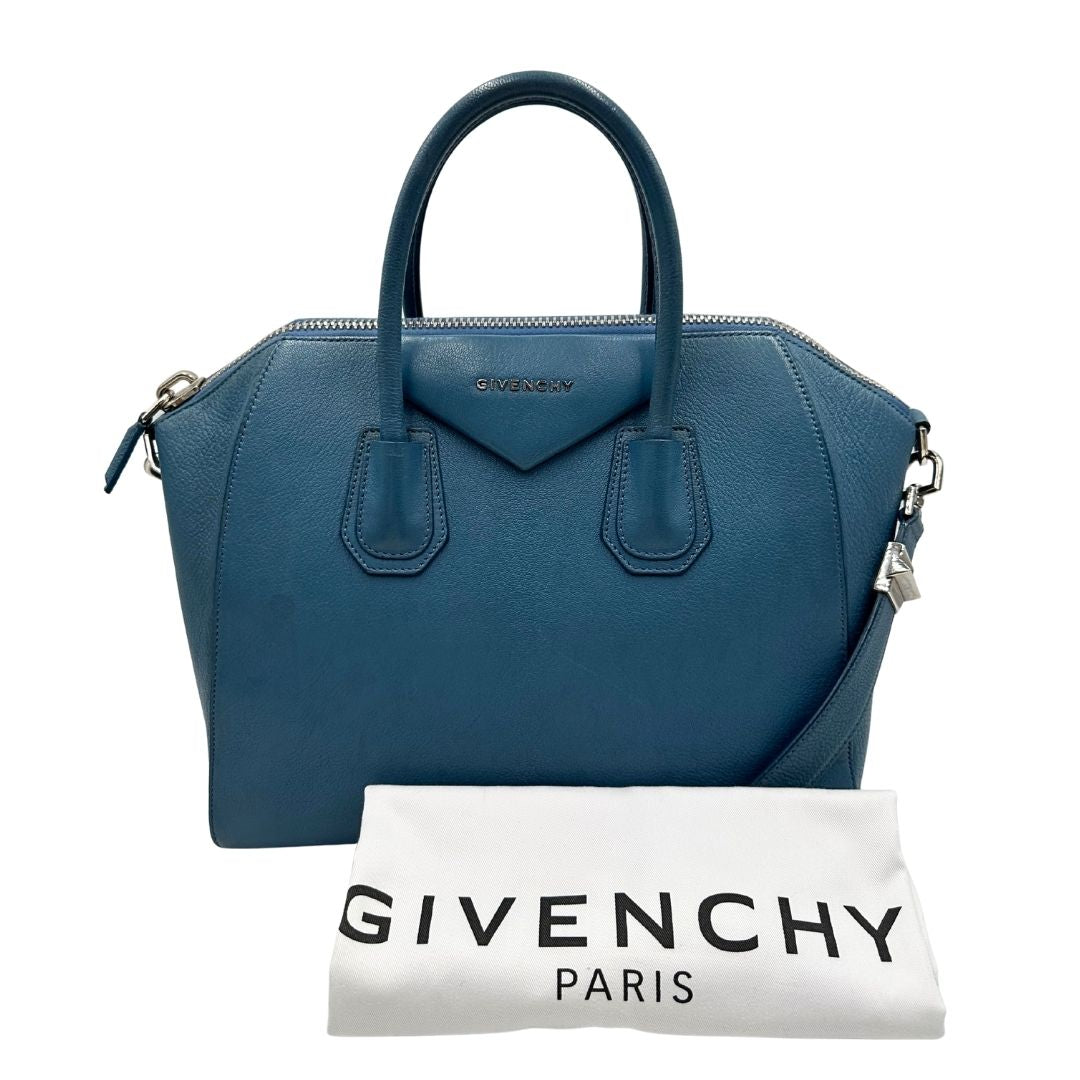Borsa Givenchy Antigona in pelle martellata blu petrolio munita di doppi manici stondati e tracolla. Parti metalliche argentate. Completa di dustbag. Originale, usato, in condizioni ottime. 