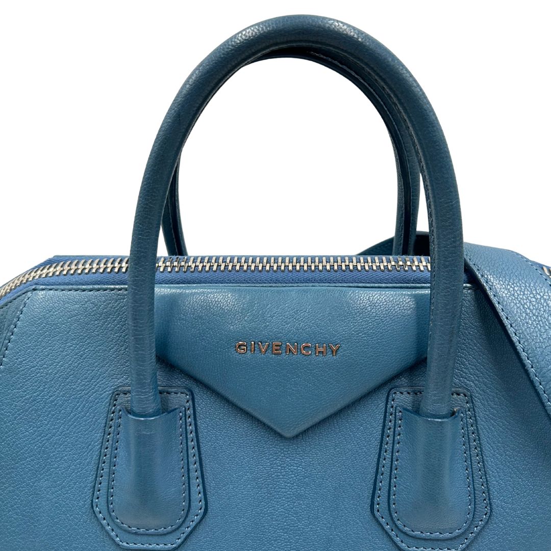 Borsa Givenchy Antigona in pelle martellata blu petrolio munita di doppi manici stondati e tracolla. Parti metalliche argentate. Completa di dustbag. Originale, usato, in condizioni ottime. 