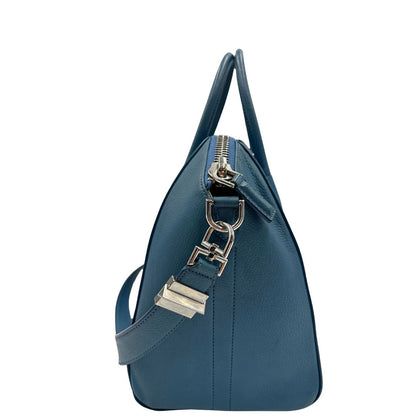 Borsa Givenchy Antigona in pelle martellata blu petrolio munita di doppi manici stondati e tracolla. Parti metalliche argentate. Completa di dustbag. Originale, usato, in condizioni ottime. 