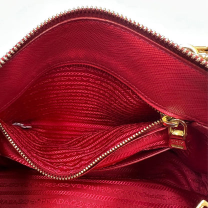 interno Borsa in pelle saffiano rossa con parti metalliche dorate; munita di doppi manici stondati e una tracolla amovibile e regolabile. 