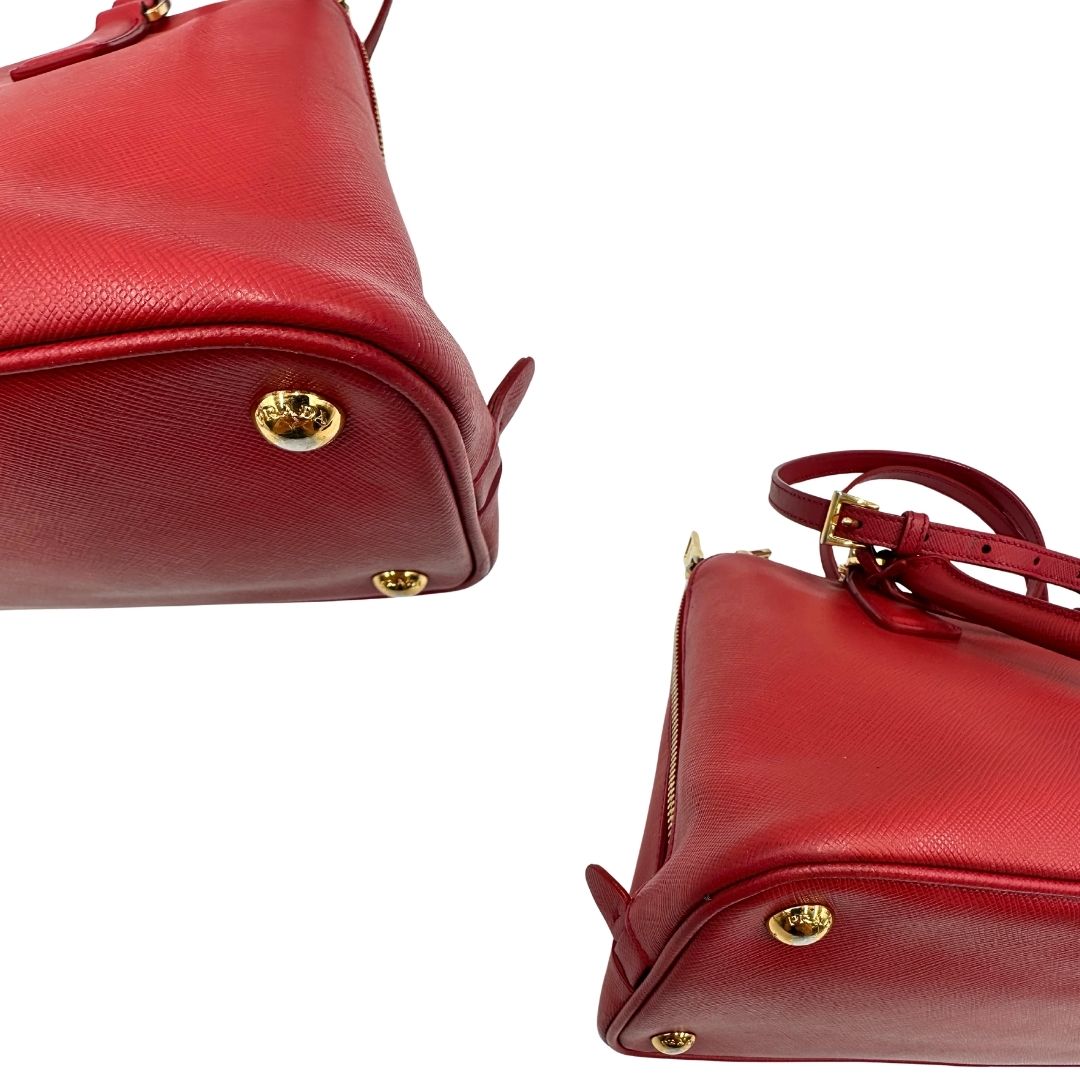 angoli Borsa in pelle saffiano rossa con parti metalliche dorate; munita di doppi manici stondati e una tracolla amovibile e regolabile. 