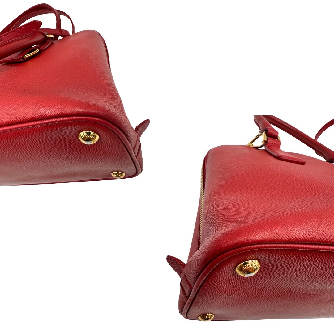 angoli Borsa in pelle saffiano rossa con parti metalliche dorate; munita di doppi manici stondati e una tracolla amovibile e regolabile. 