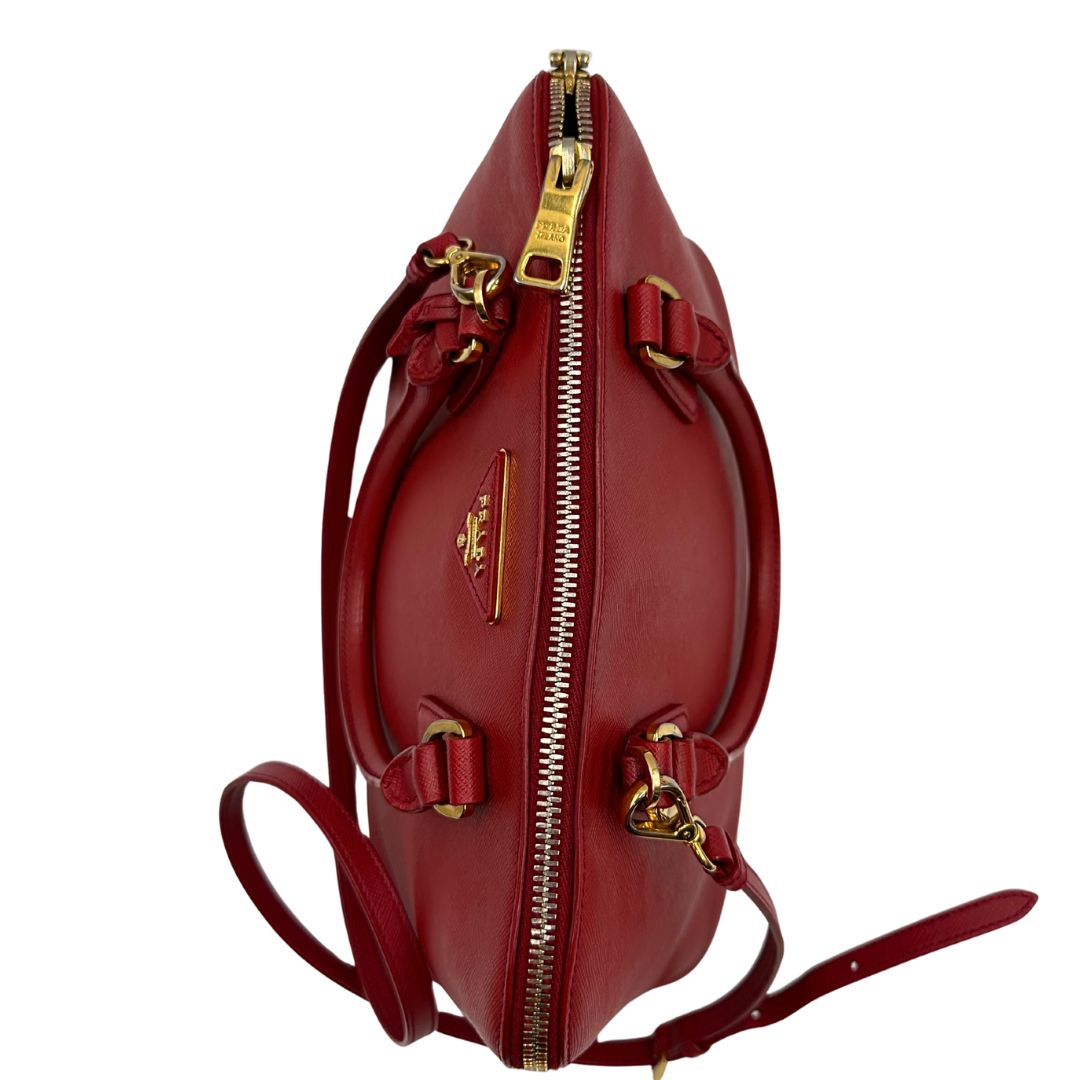 cerniera Borsa in pelle saffiano rossa con parti metalliche dorate; munita di doppi manici stondati e una tracolla amovibile e regolabile. 