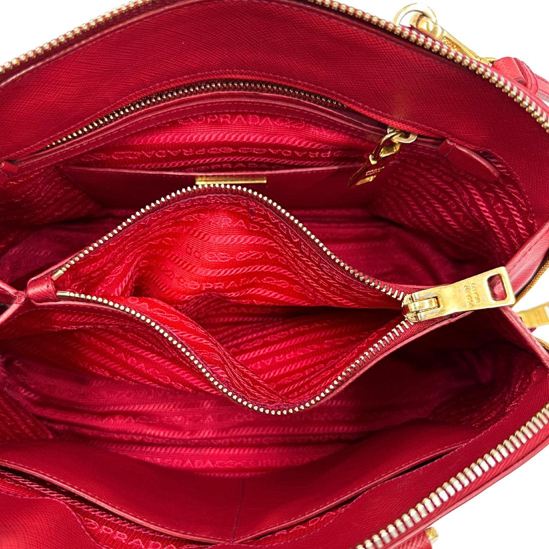interno Borsa in pelle saffiano rossa con parti metalliche dorate; munita di doppi manici stondati e una tracolla amovibile e regolabile. 