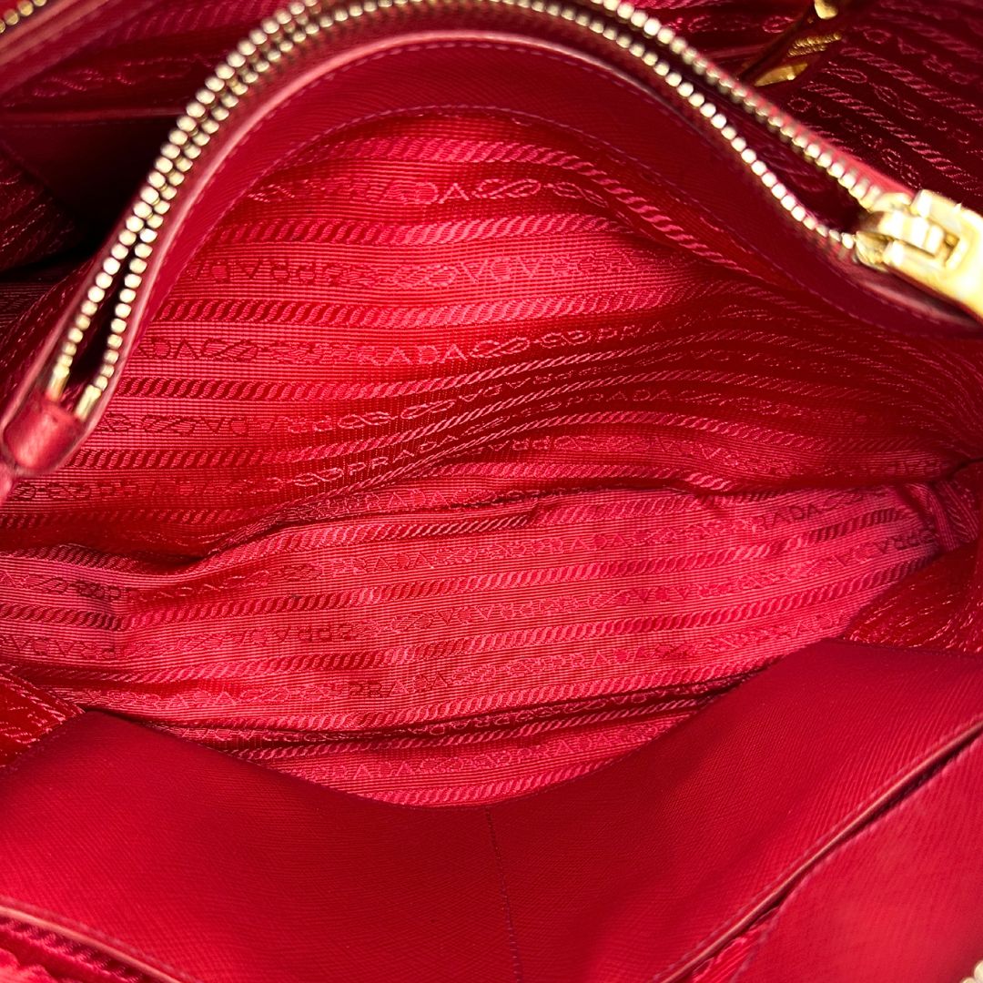interno Borsa in pelle saffiano rossa con parti metalliche dorate; munita di doppi manici stondati e una tracolla amovibile e regolabile. 