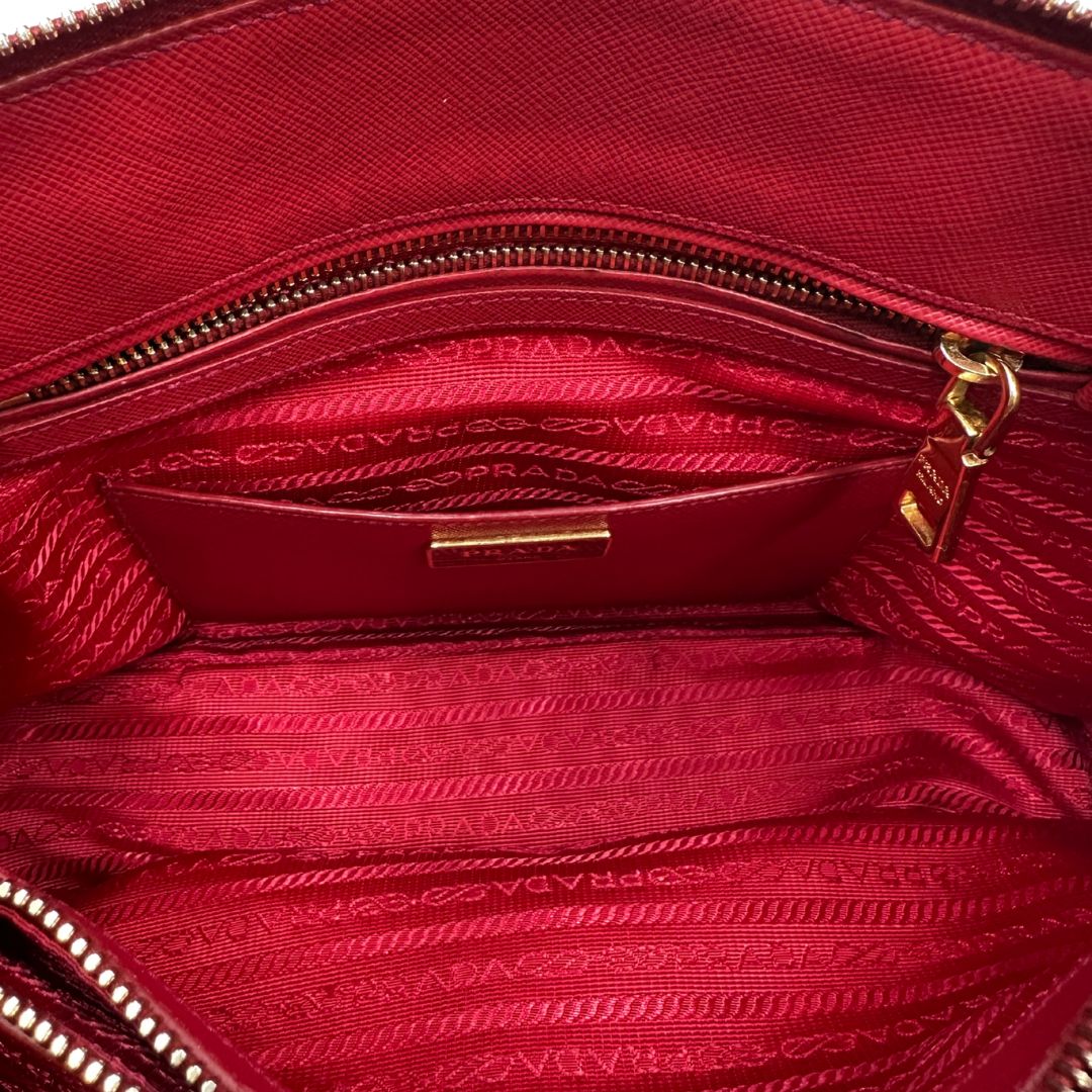 interno Borsa in pelle saffiano rossa con parti metalliche dorate; munita di doppi manici stondati e una tracolla amovibile e regolabile. 