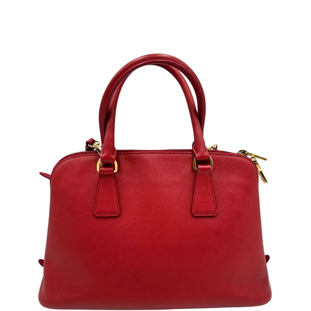 retro Borsa in pelle saffiano rossa con parti metalliche dorate; munita di doppi manici stondati e una tracolla amovibile e regolabile. 