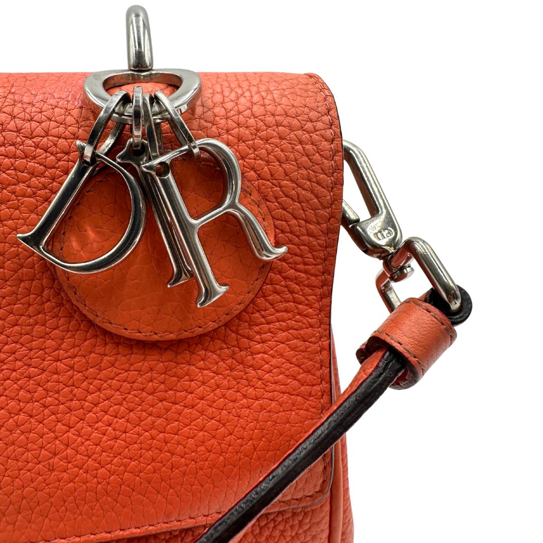 Charm di una borsa Christian Dior Bedior in pelle corallo. Manico rigido e tracolla amovibile e regolabile. Parti metalliche argentate.