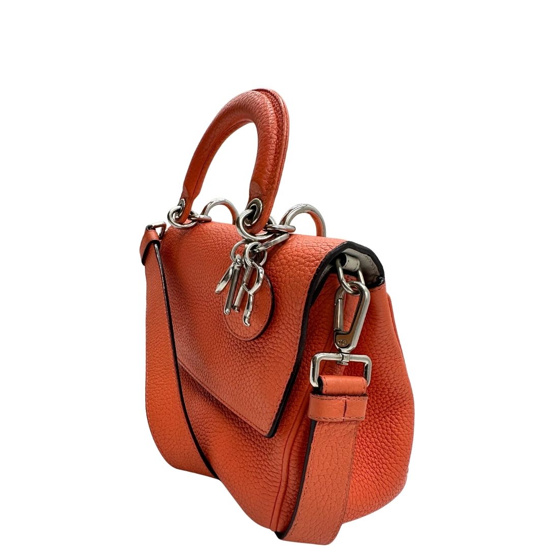 Laterale destro di una borsa Christian Dior Bedior in pelle corallo. Manico rigido e tracolla amovibile e regolabile. Parti metalliche argentate.