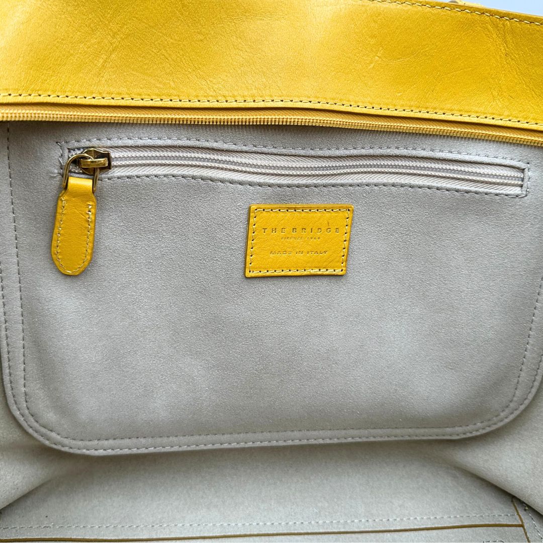 interno Borsa The Bridge in pelle gialla con parti metalliche dorate; munita di doppi manici, da indossare a spalla 