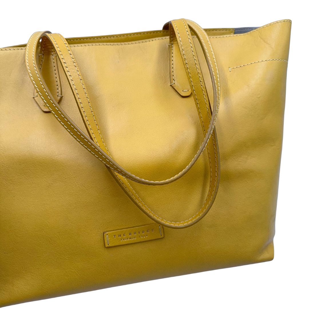 manici Borsa The Bridge in pelle gialla con parti metalliche dorate; munita di doppi manici, da indossare a spalla 