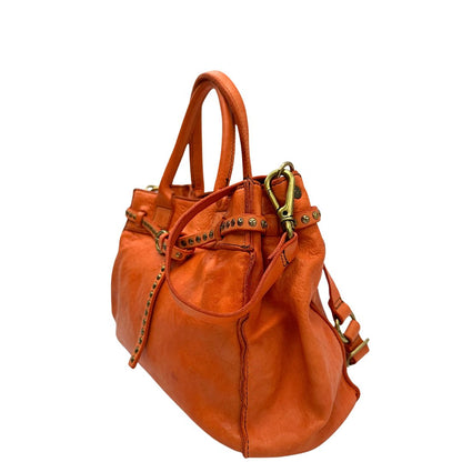 Laterale destro di una satchel Campomaggi in pelle arancione; munita di doppi manici e tracolla amovibile e regolabile. Parti metalliche dorate. Completa di dustbag e crema idratante per pelli.