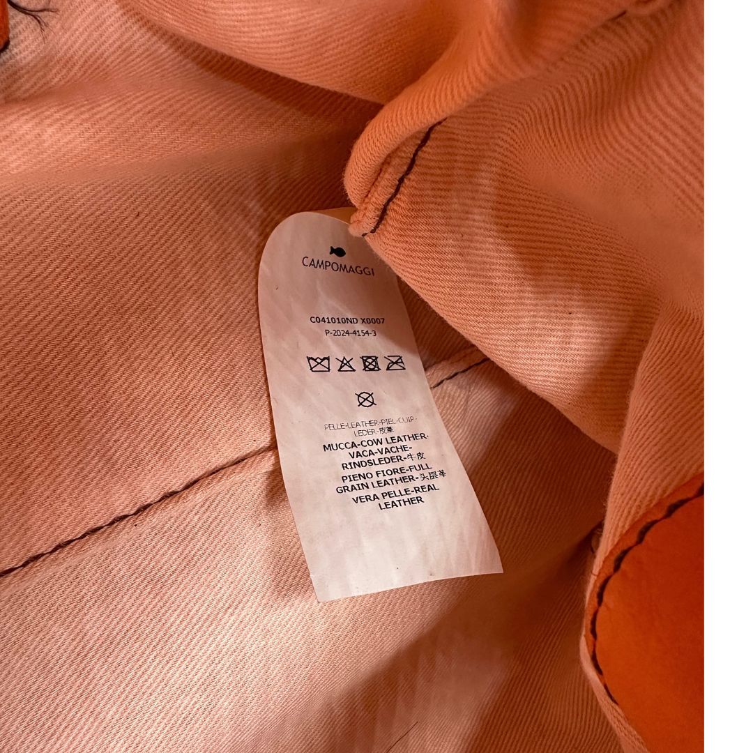Codice di una satchel Campomaggi in pelle arancione; munita di doppi manici e tracolla amovibile e regolabile. Parti metalliche dorate. Completa di dustbag e crema idratante per pelli.