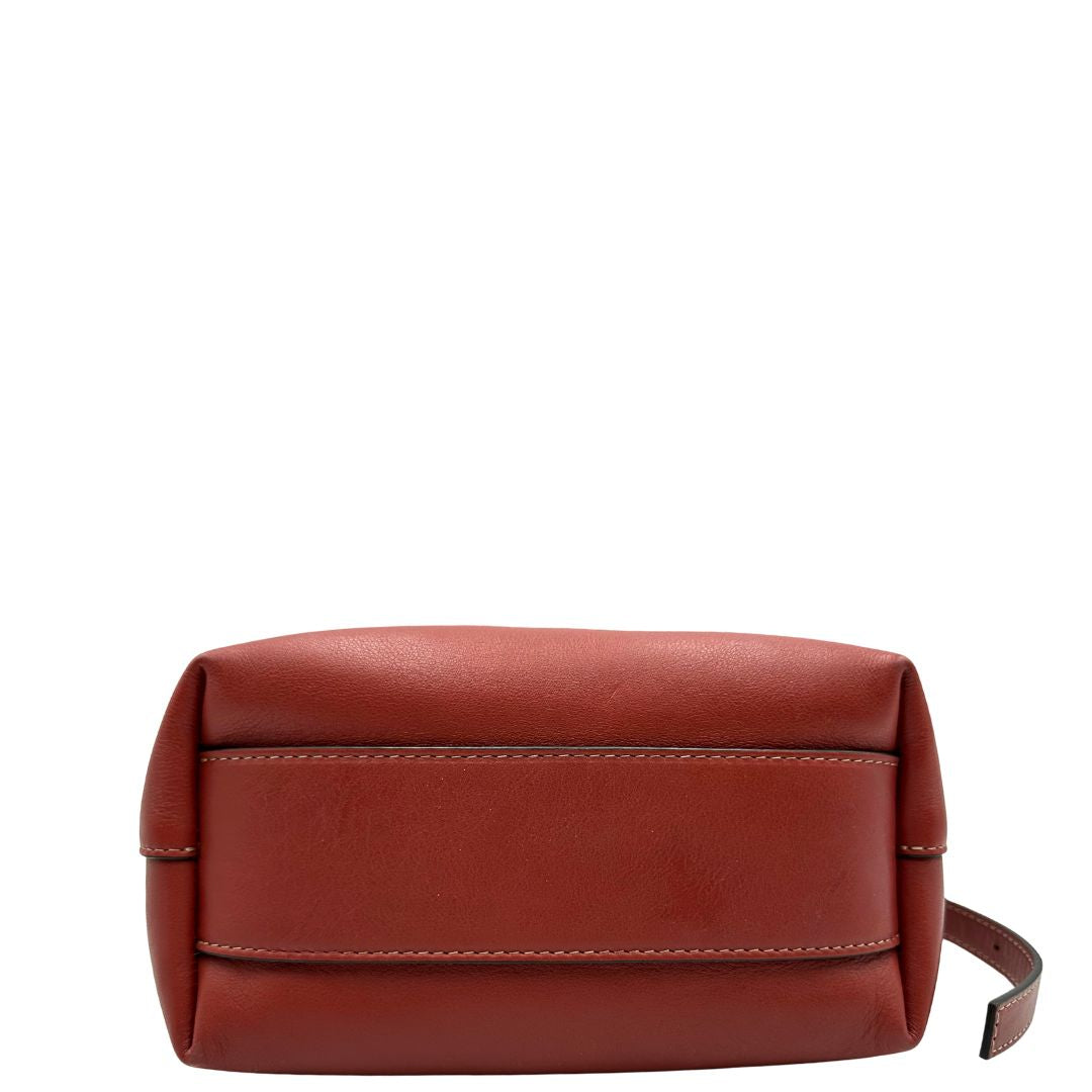 Base di una borsa a secchiello Hags in pelle color marrone bruciato con manico regolabile. Parti metalliche argentate. Indossabile a spalla o a tracolla. Completa di dustbag.