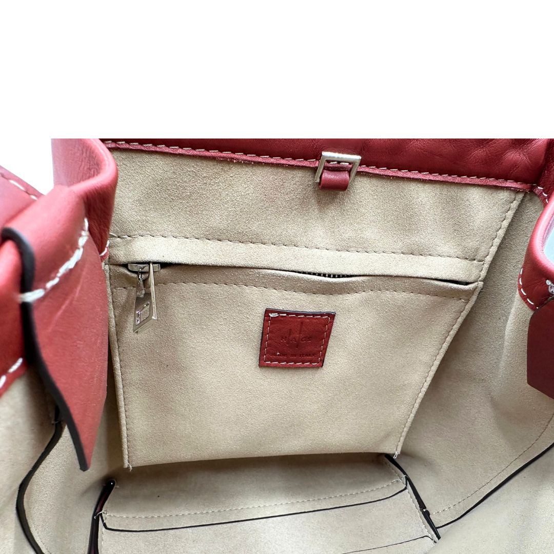 Interno di una borsa a secchiello Hags in pelle color marrone bruciato con manico regolabile. Parti metalliche argentate. Indossabile a spalla o a tracolla. Completa di dustbag.