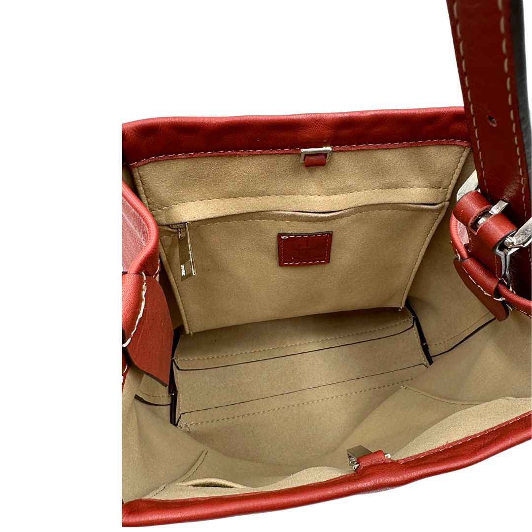 Interno di una borsa a secchiello Hags in pelle color marrone bruciato con manico regolabile. Parti metalliche argentate. Indossabile a spalla o a tracolla. Completa di dustbag.