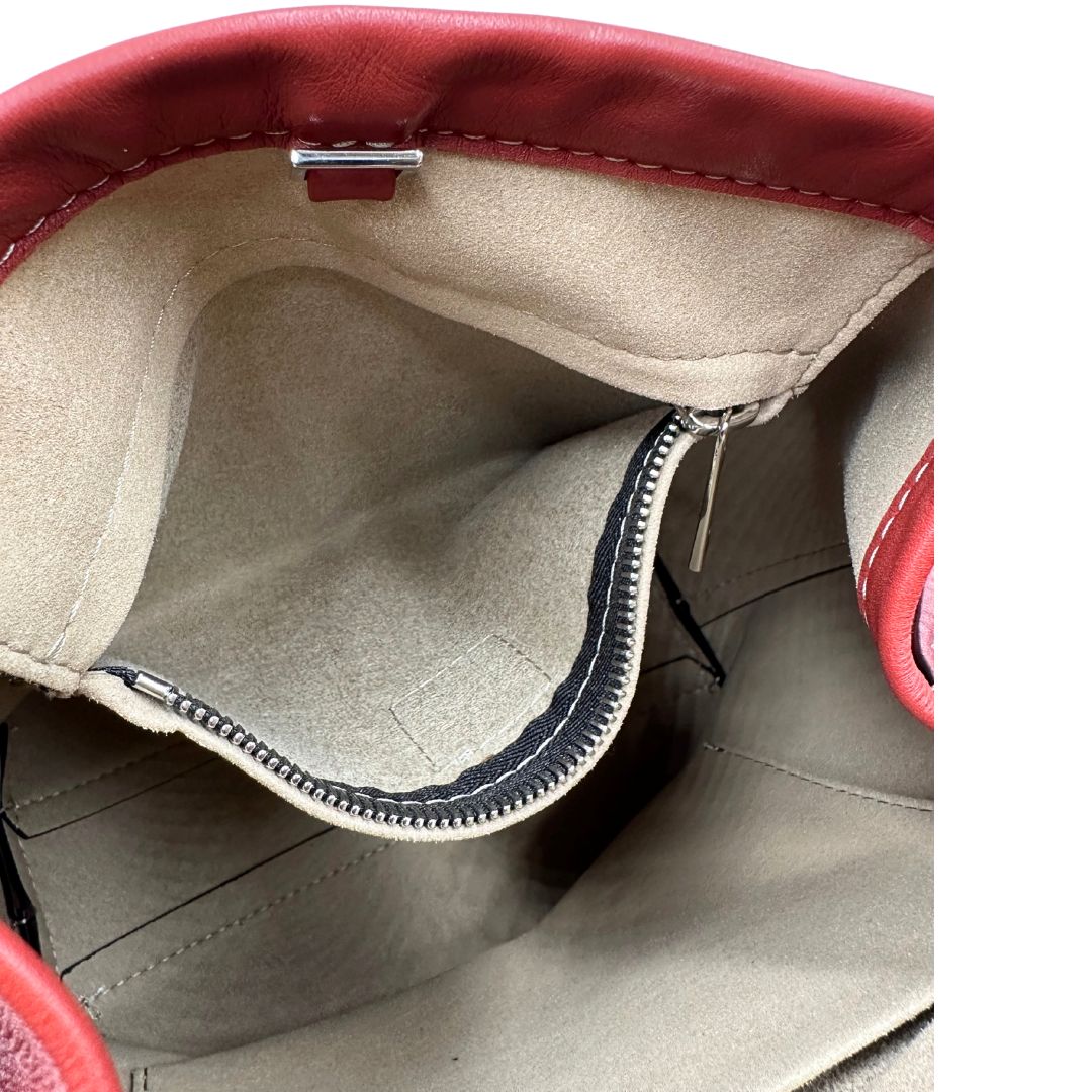 Interno di una borsa a secchiello Hags in pelle color marrone bruciato con manico regolabile. Parti metalliche argentate. Indossabile a spalla o a tracolla. Completa di dustbag.