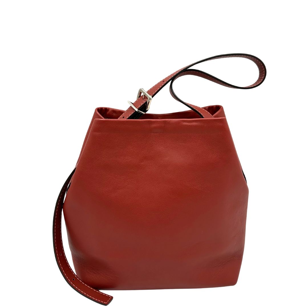 Retro di una borsa a secchiello Hags in pelle color marrone bruciato con manico regolabile. Parti metalliche argentate. Indossabile a spalla o a tracolla. Completa di dustbag.