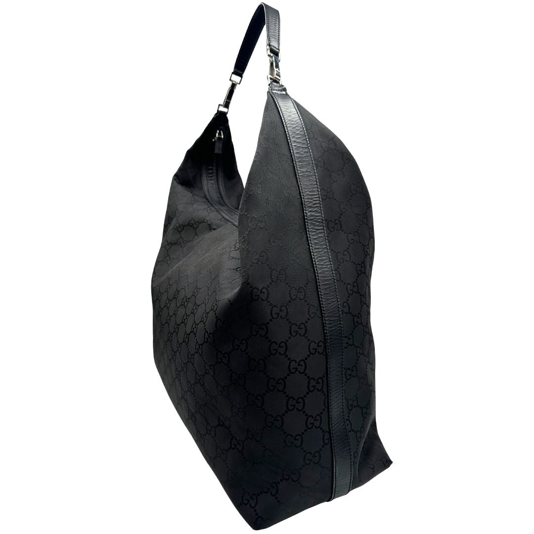 Laterale destro di un borsone Gucci in tessuto trama GG Supreme con parti metalliche argentate e finiture in pelle tono su tono; munita di un manico singolo amovibile. Indossabile a spalla.