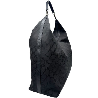 Laterale sinistro di un borsone Gucci in tessuto trama GG Supreme con parti metalliche argentate e finiture in pelle tono su tono; munita di un manico singolo amovibile. Indossabile a spalla.