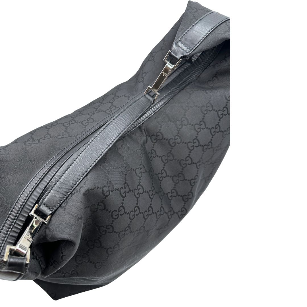 Vista dall'alto di un borsone Gucci in tessuto trama GG Supreme con parti metalliche argentate e finiture in pelle tono su tono; munita di un manico singolo amovibile. Indossabile a spalla.