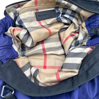 Borsa Burberry Tote Buckleigh in nylon viola con finiture in pelle nera e parti metalliche effetto renio. Munita di doppi manici, da indossare a spalla. Originale, usato, in condizioni ottime. 