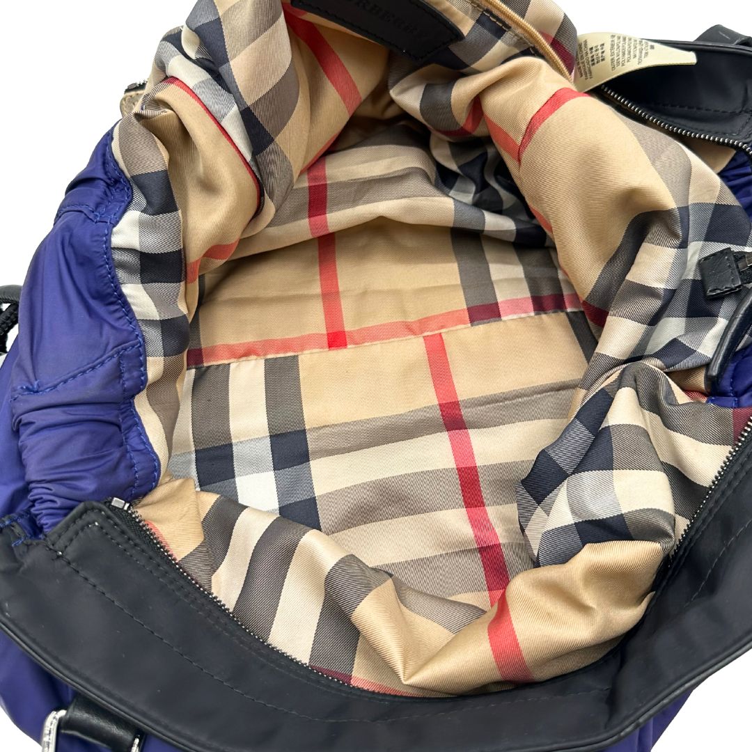 Borsa Burberry Tote Buckleigh in nylon viola con finiture in pelle nera e parti metalliche effetto renio. Munita di doppi manici, da indossare a spalla. Originale, usato, in condizioni ottime. 