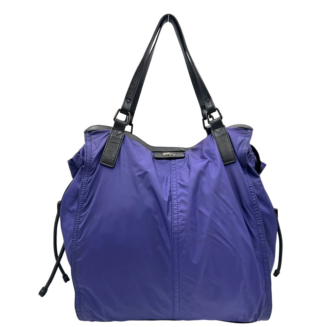 Borsa Burberry Tote Buckleigh in nylon viola con finiture in pelle nera e parti metalliche effetto renio. Munita di doppi manici, da indossare a spalla. Originale, usato, in condizioni ottime. 