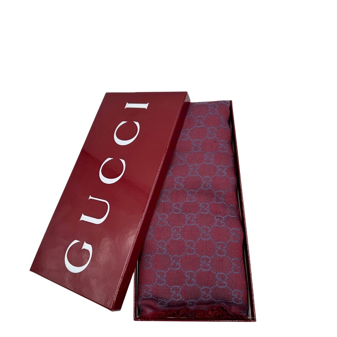 Scialle Gucci in misto lana e seta bicolore; bordeaux e blu con trama GG, e bori sfrangiati. Completo di scatola. Originale, usato, in condizioni ottime. 