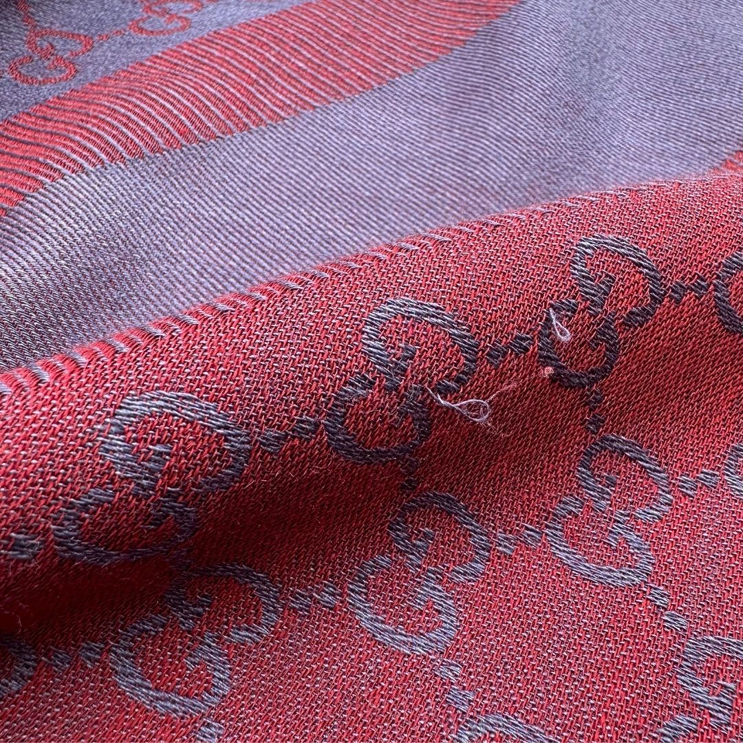 Scialle Gucci in misto lana e seta bicolore; bordeaux e blu con trama GG, e bori sfrangiati. Completo di scatola. Originale, usato, in condizioni ottime. 