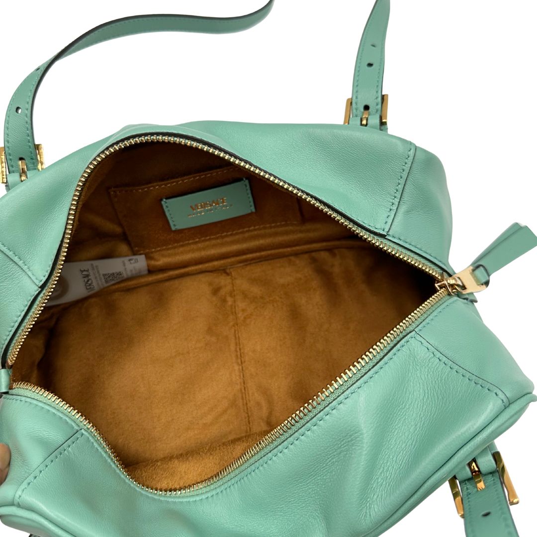 Interno Bauletto Versace in pelle verde tiffany con parti metalliche dorate e doppi manici leggermente regolabili. Rifinita con logo lettering sul front e medusa sulla clochette rimovibile. Completo di corredo. Originale, usato, in condizioni ottime. 