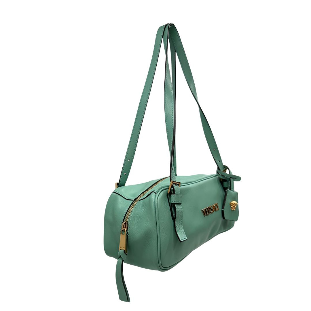 Laterale Bauletto Versace in pelle verde tiffany con parti metalliche dorate e doppi manici leggermente regolabili. Rifinita con logo lettering sul front e medusa sulla clochette rimovibile. Completo di corredo. Originale, usato, in condizioni ottime. 