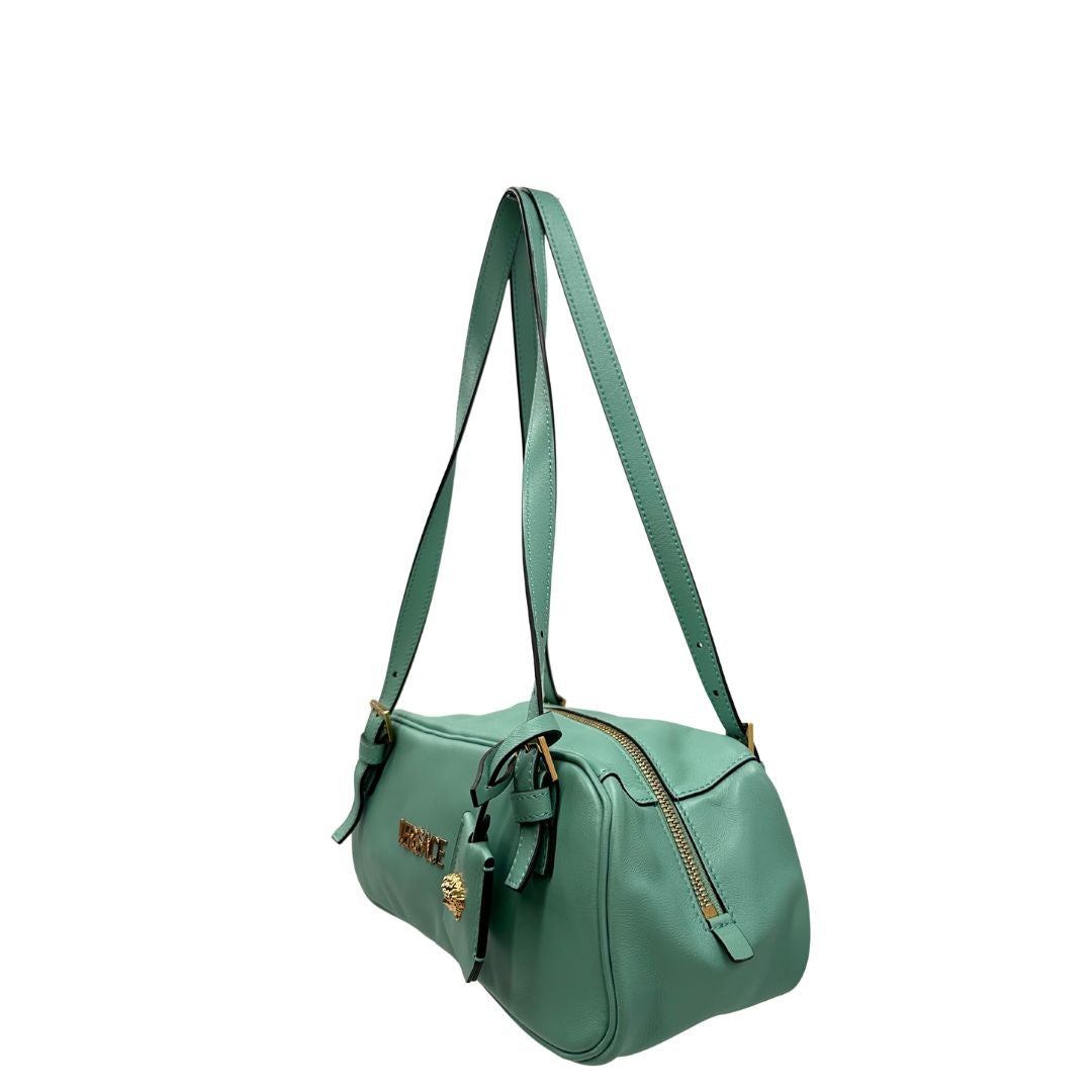 Laterale Bauletto Versace in pelle verde tiffany con parti metalliche dorate e doppi manici leggermente regolabili. Rifinita con logo lettering sul front e medusa sulla clochette rimovibile. Completo di corredo. Originale, usato, in condizioni ottime. 