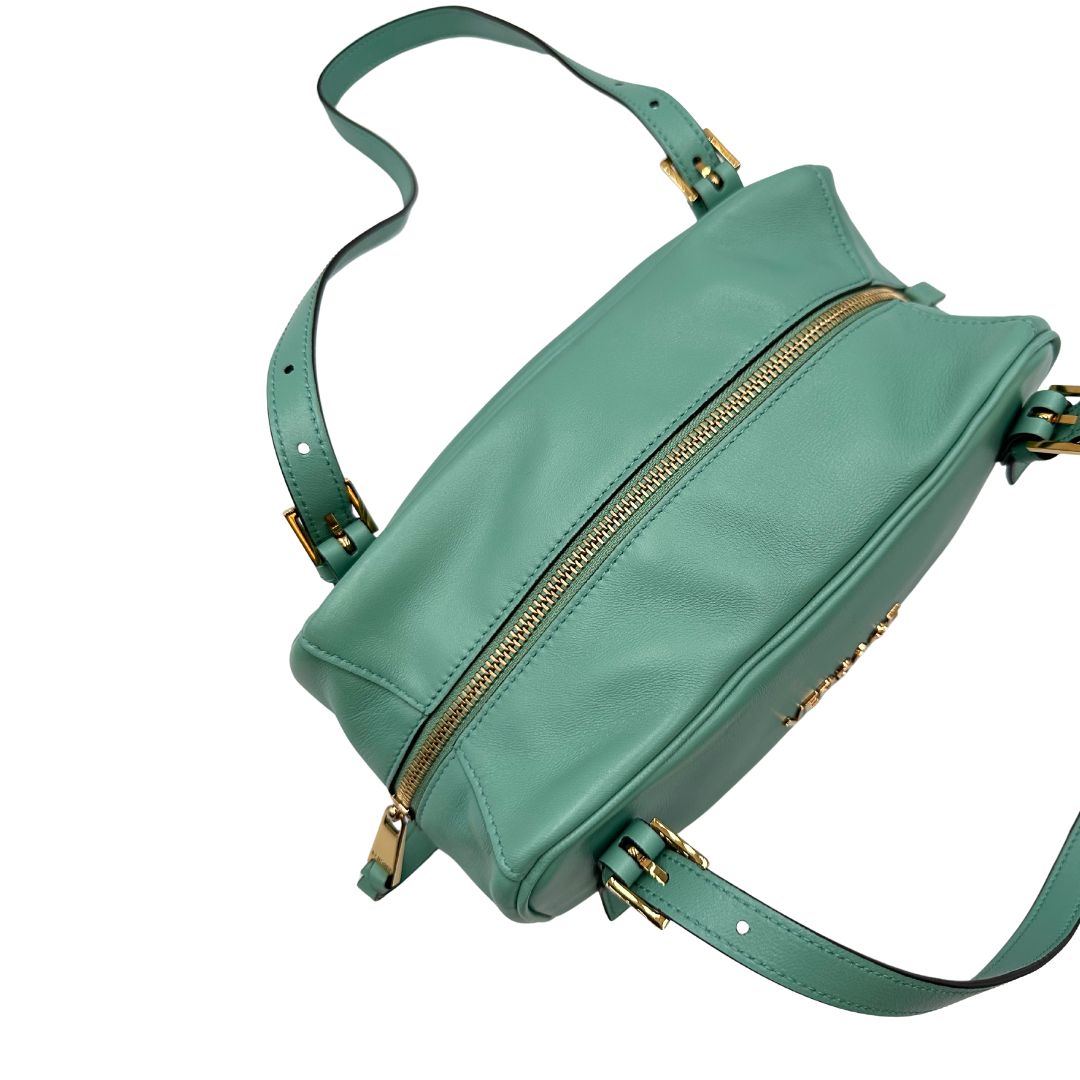 Bauletto Versace in pelle verde tiffany con parti metalliche dorate e doppi manici leggermente regolabili. Rifinita con logo lettering sul front e medusa sulla clochette rimovibile. Completo di corredo. Originale, usato, in condizioni ottime. 