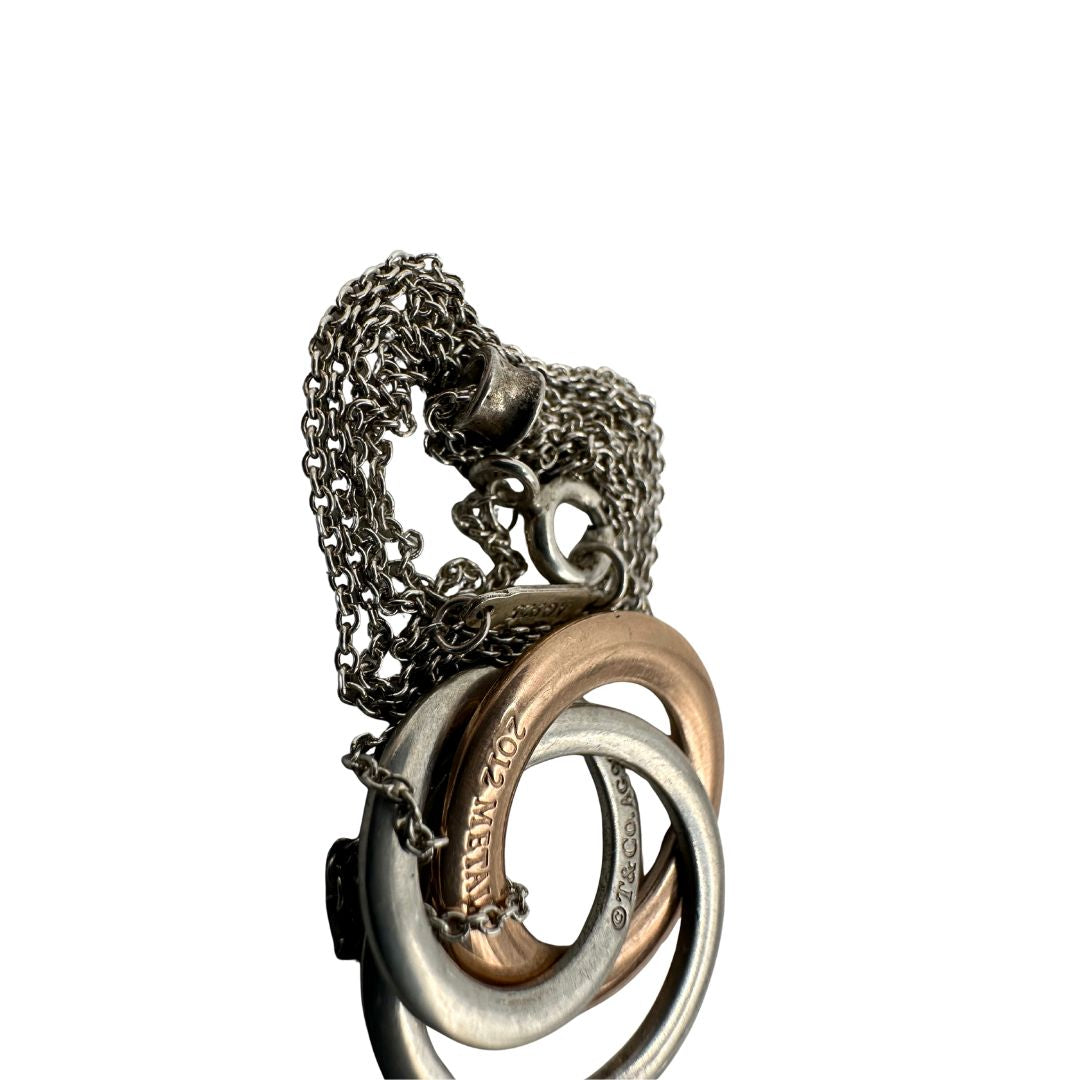 Collana Tiffany&amp;Co. Three Interlocking Rings della collezione Elsa Peretti , in argento 925 con tre ciondoli a cerchio intrecciati, di cui uno color oro. Completo di sacchetto antipolvere. Originale, usato, in condizioni ottime. 