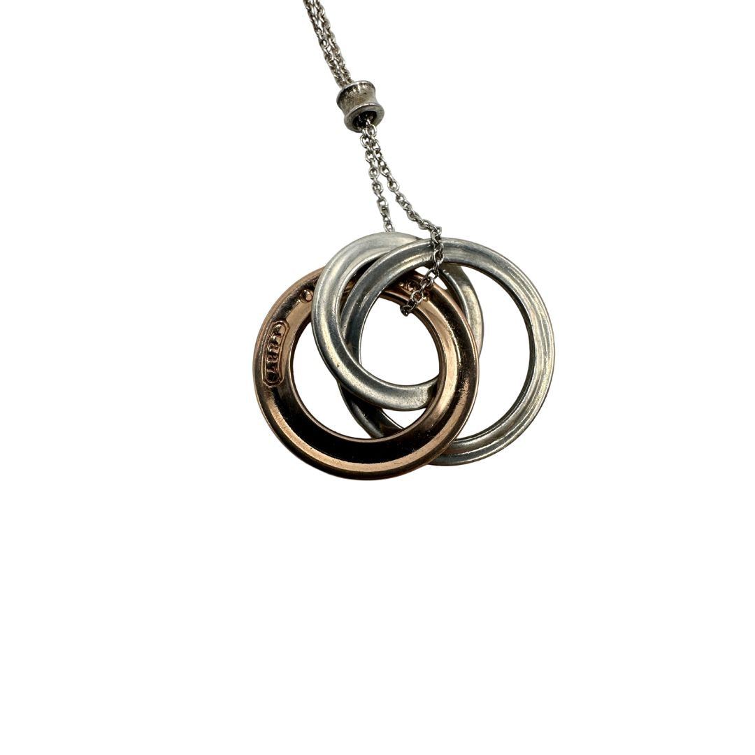 Collana Tiffany&amp;Co. Three Interlocking Rings della collezione Elsa Peretti , in argento 925 con tre ciondoli a cerchio intrecciati, di cui uno color oro. Completo di sacchetto antipolvere. Originale, usato, in condizioni ottime. 