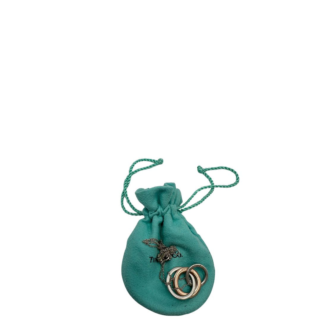 Collana Tiffany&amp;Co. Three Interlocking Rings della collezione Elsa Peretti , in argento 925 con tre ciondoli a cerchio intrecciati, di cui uno color oro. Completo di sacchetto antipolvere. Originale, usato, in condizioni ottime. 