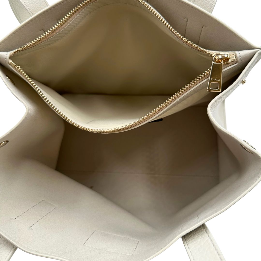 interno Borsa Furla in pelle martellata color bianco latte con parti metalliche oro chiaro; munita di doppi manici, indossabile a spalla 