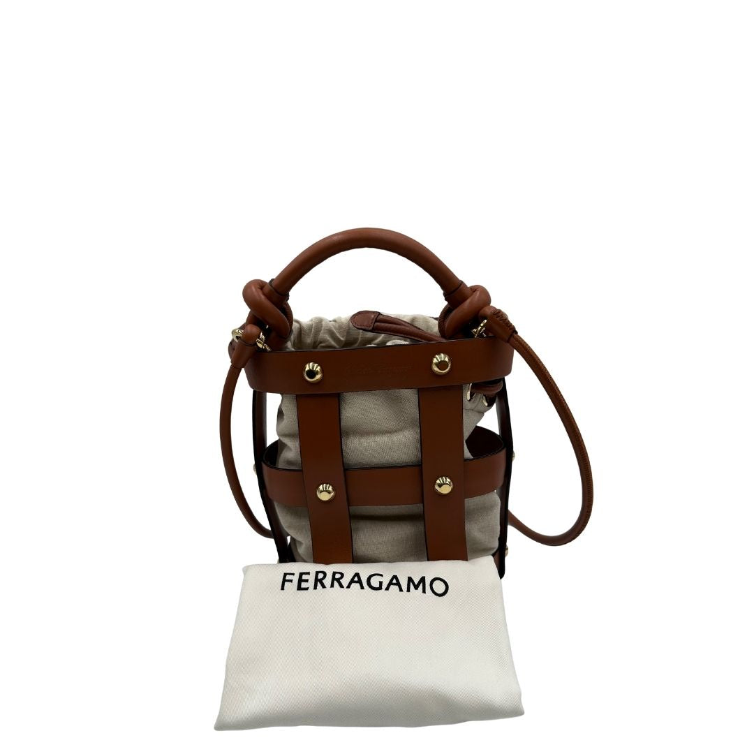 Borsa a secchiello Salvatore Ferragamo in pelle marrone cognac con sacca interna in tela beige con chiusura a coulisse. Munita di un manico stondato e tracolla, parti metalliche dorate. Completa di dustbag. Originale, usato, in condizioni ottime. 